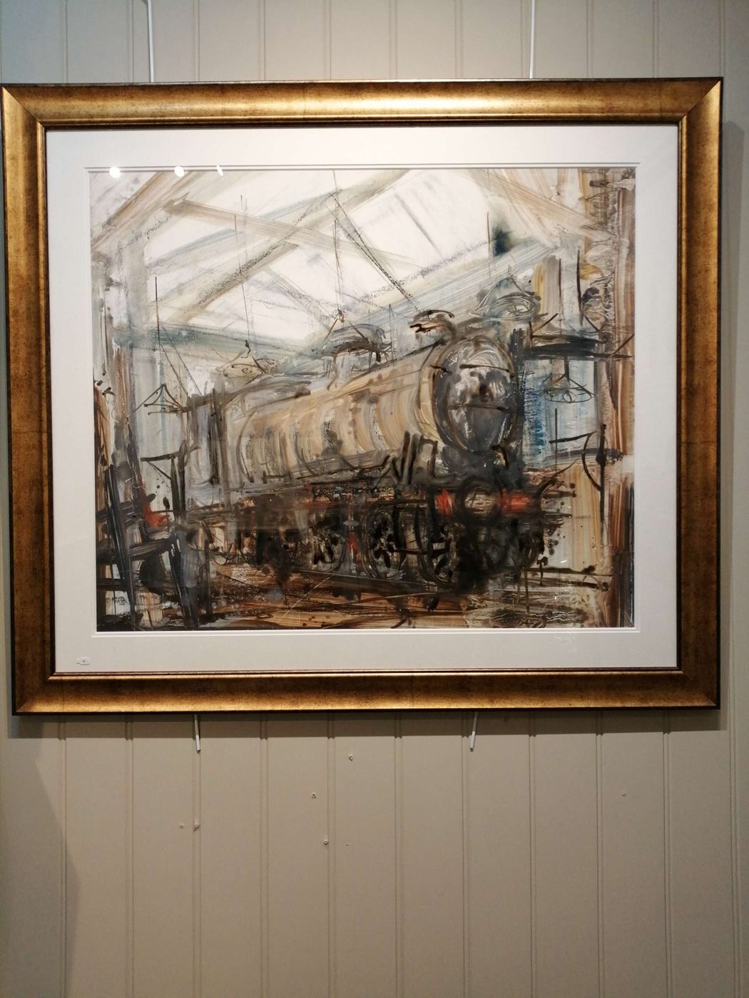 Gilt-framed painting of a steam locomotive in a roundhouse, on the wall at Mere Antiques, Topsham